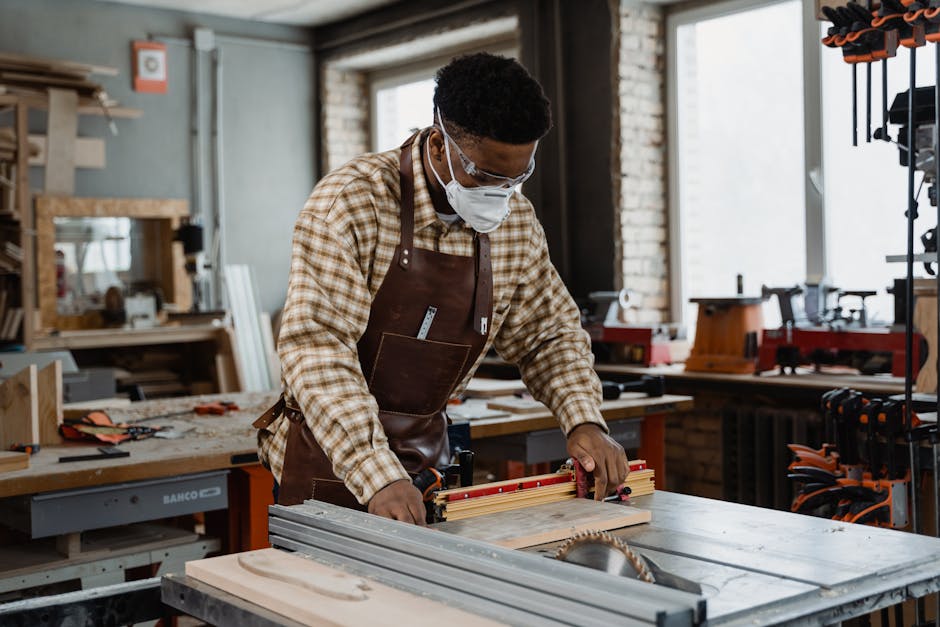 Artisan wearing an apron and mask, precisely measuring and cutting wood in a workshop setting.